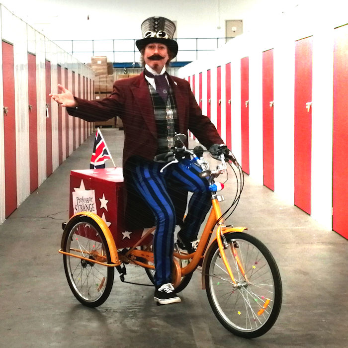 Victorian Steampunk magician Professor Strange ridaround act on trike cycle